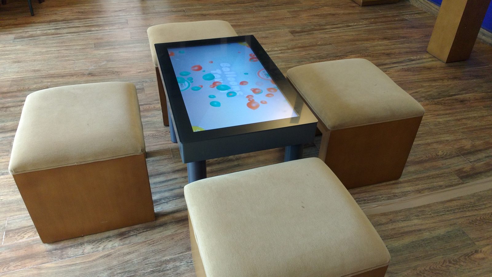 Interactive touch table surrounded by four upholstered stools